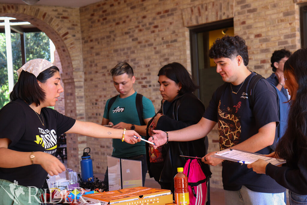 Public affairs graduate student Estrella Torres, the Texas Rising regional program coordinator (from left), helps nursing freshman David Tamez check his voter registration status Oct. 7 outside the University Library on the Brownsville campus. Also shown are management senior Gabriel Morales, visual communication design senior Christalinda Beltran and integrated health science sophomore Dulceaylin Ramirez. Venisha Col贸n/THE RIDER