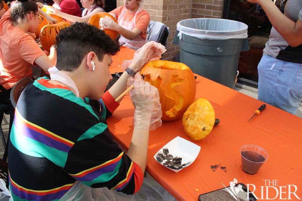 Music sophomore Marko Muñoz paints over his pumpkin during the carving/painting contest Wednesday outside the Student Union on the Edinburg campus. Raquel Cazares/THE RIDER