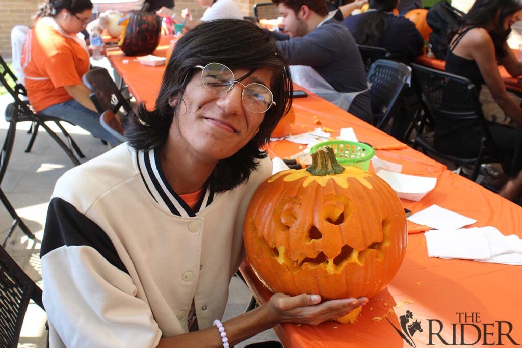 Hospitality and tourism freshman Miguel Chasco poses with his finished pumpkin during the carving/painting contest Wednesday outside the Student Union on the Edinburg campus. Raquel Cazares/THE RIDER