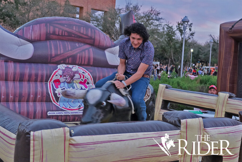 English senior Jesus Pruneda rides the mechanical bull during the Vaqueros Boots & BBQ event Thursday evening on the Quad on the Edinburg campus.
Angel Ballesteros/THE RIDER
