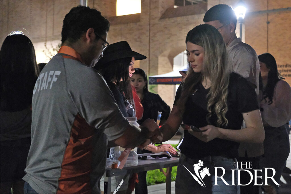 Jordan Saldana (left), a student union employee, helps exercise science freshman Liliane Martinez check in during the Vaqueros Boots & BBQ event Thursday evening on the Quad on the Edinburg campus.
Angel Ballesteros/THE RIDER